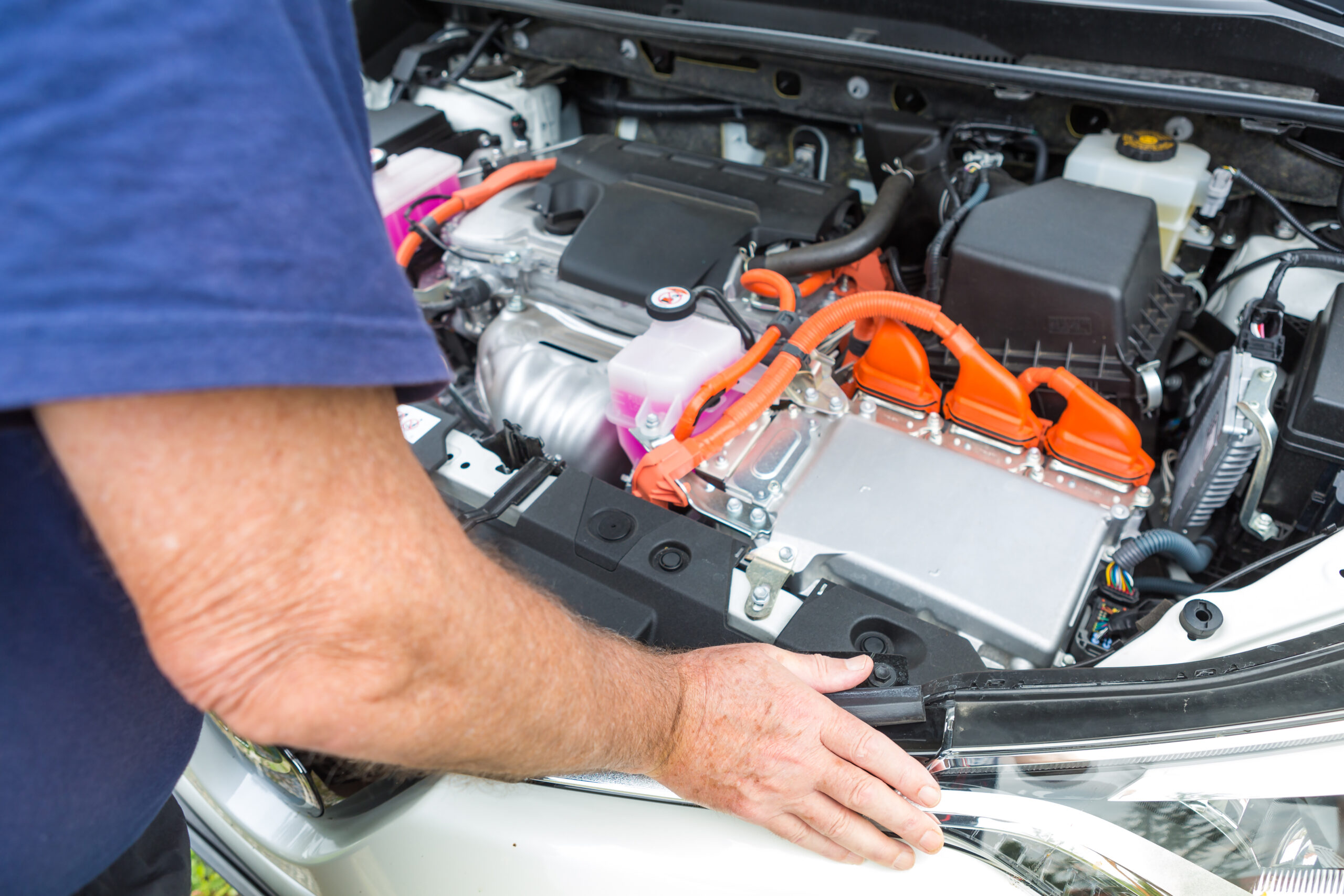 Senior man leaning over the interior of a hybrid car powered bot