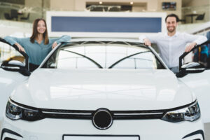 man and women on each side of new car