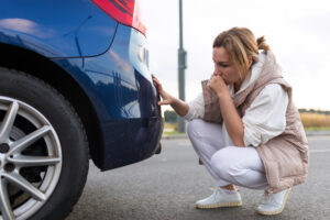 women looking at a scratch on her bumper 