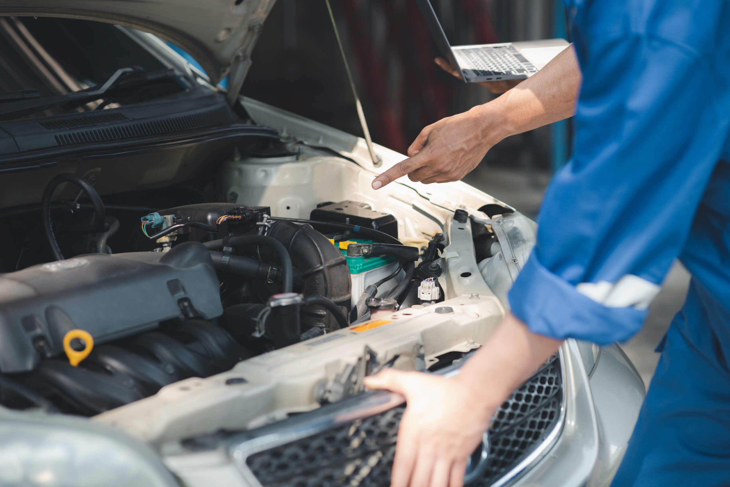 Two professional car mechanics are helping to inspect a customer