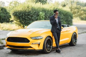 man leans against yellow GT mustang 